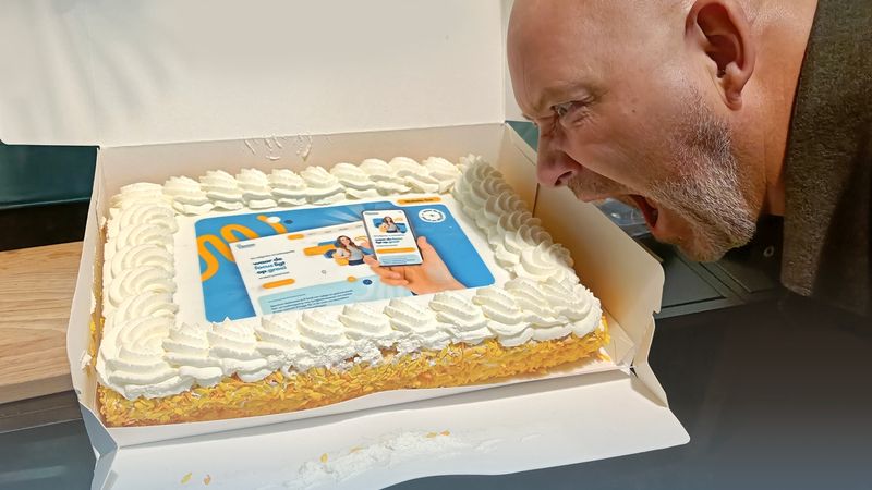 Man bijt in een feestelijke taart met daarop de nieuwe Spectrum Multimedia website.