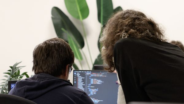 Deelnemer met krullend haar gefotografeerd van achteren in een groepssetting.